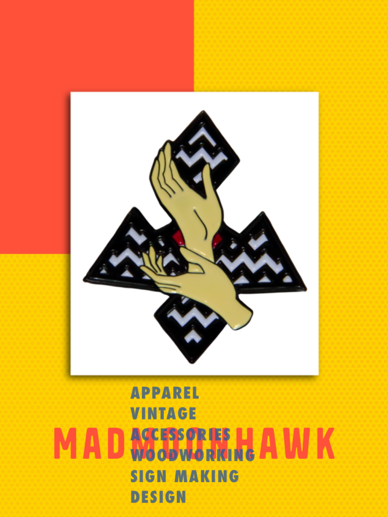 a red and yellow blocked page with a white frame in the middle, lapel pin with hands and black and white zig zags behind it. Captioned MADMOONHAWK: apparel, vintage, accessories, wood working, and design 