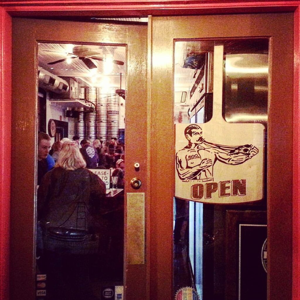 pizza paddle shaped OPEN sign hanging in the front windowed door of a restaurant