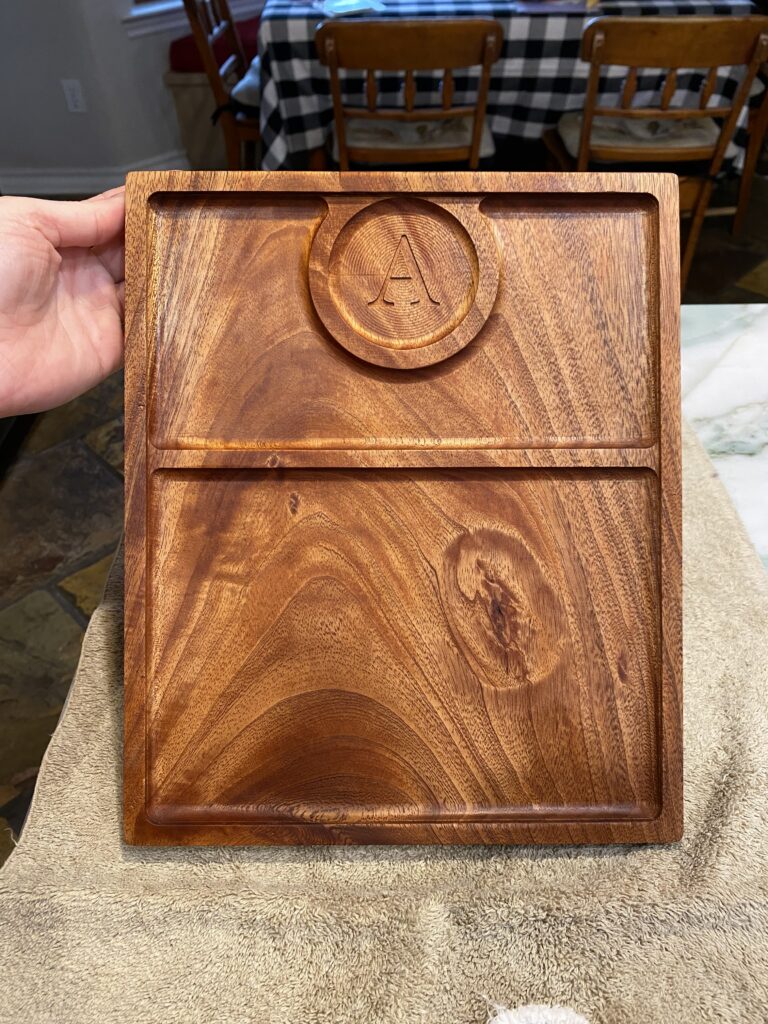 rolling tray carved into african mahogany being held up by a hand